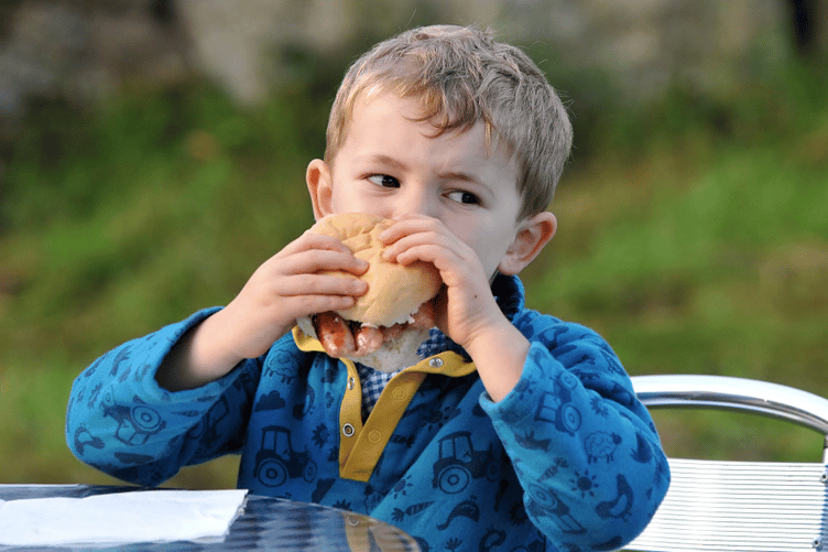 Three year old  Wilf Caunter tucks into a bacon bap.