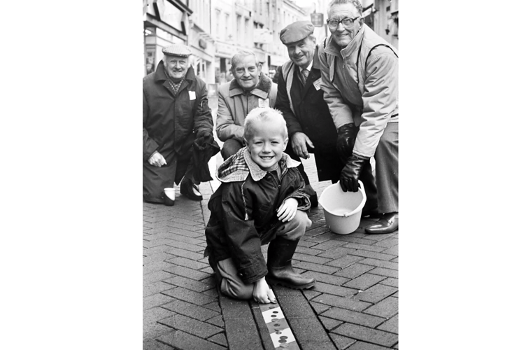 Five year old Christopher Beswick makes his contribution to the Moose Lodge line of pennies in Teignmouth’s Bank Street as part of the 1990 Children in Need appeal