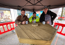Shed members celebrate with a cuppa after installing tree stump table 