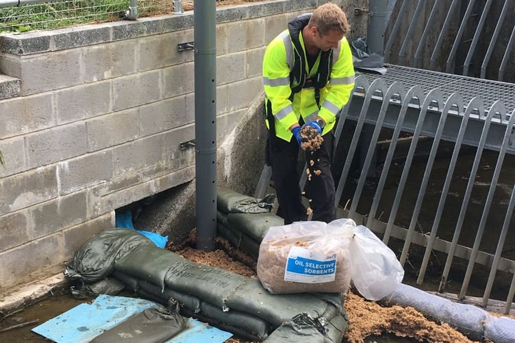 An Environment Agency officer adds oil absorbents where diesel was flowing from the land drain into the Coney Gut diversion channel.