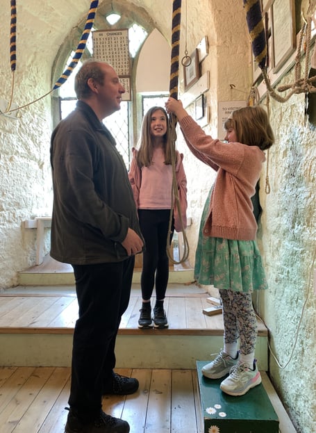 Bell ringer Roger Dickinson coaching his daughter Eleanor on bell handling while his older daughter, Grace, looks on. Photo contributed 